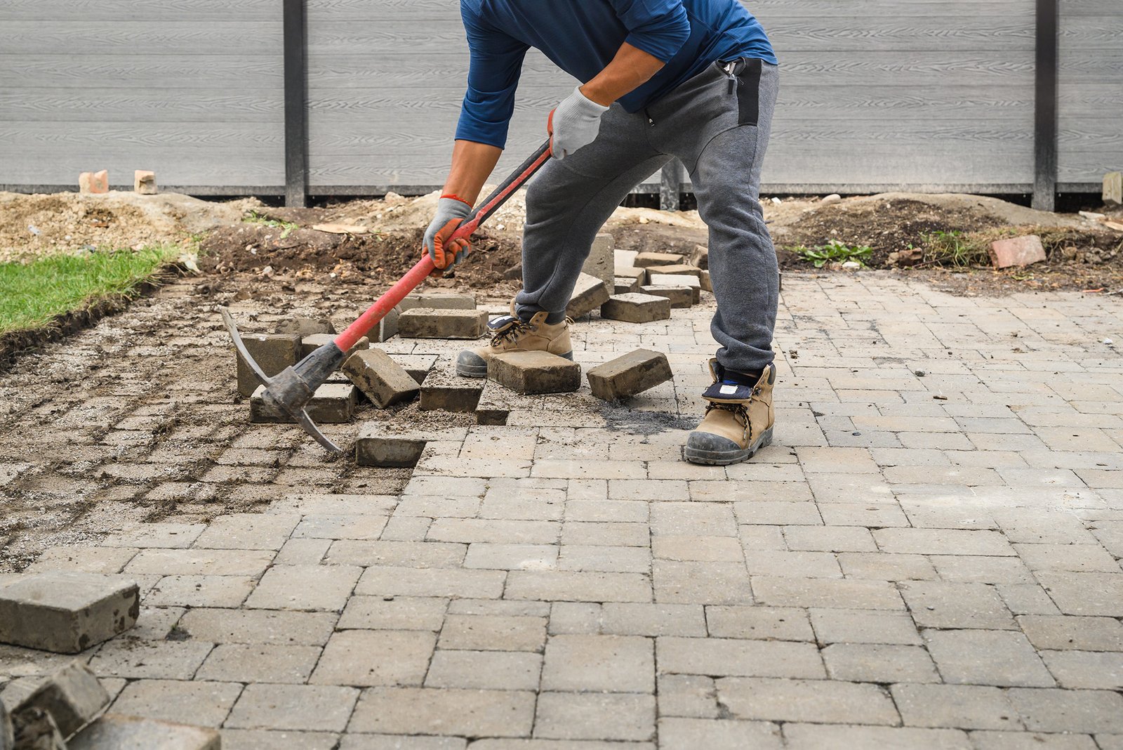 Man Loosening Pavers with Pick Mattock